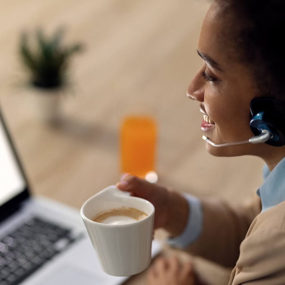 happy-african-american-businesswoman-drinking-coffee-conference-call-laptop